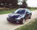 2000 Dodge Neon - A dark blue sedan is parked on a dirt road with trees and grass in the background.