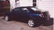 2000 Dodge Neon - This dark blue 2000 Dodge Neon sedan is parked in a driveway next to a house.