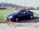 2000 Dodge Neon - A dark blue 2000 Dodge Neon sedan is parked on a gravel lot next to a grassy area.