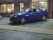 2000 Dodge Neon - A blue sedan with a spoiler is parked in front of a building. The vehicle appears to be a 2000 Dodge Neon.