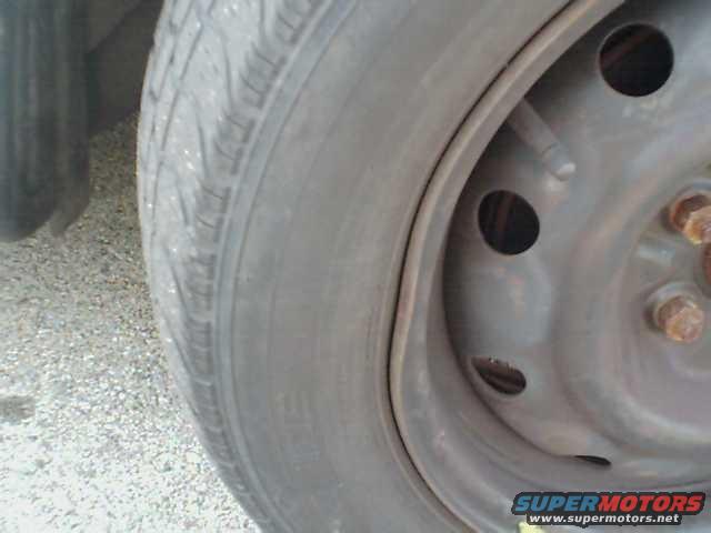 Close-up of a tire and steel wheel with visible lug nuts