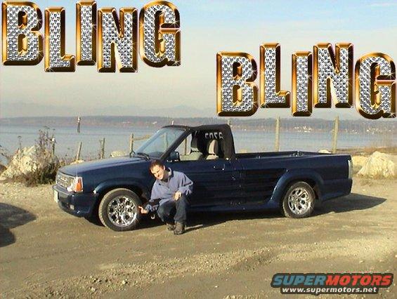 Blue pickup truck with a person pointing at the front wheel