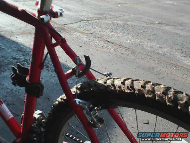 Red bicycle frame and knobby tire with mud on the tread