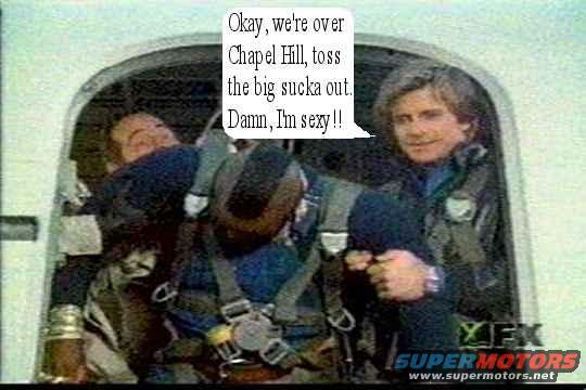 Two men in a cockpit, one is wearing a parachute harness