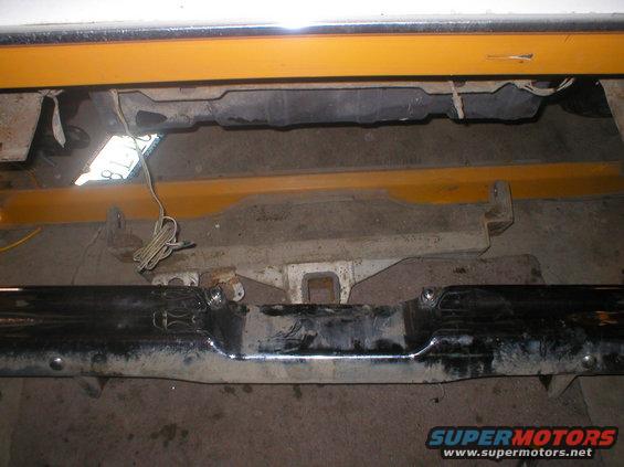 Rear bumper assembly with tow hitch receiver and wiring. Yellow support beams visible above
