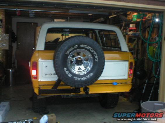 Yellow and white Ford Bronco, rear view, spare tire on tailgate, in garage