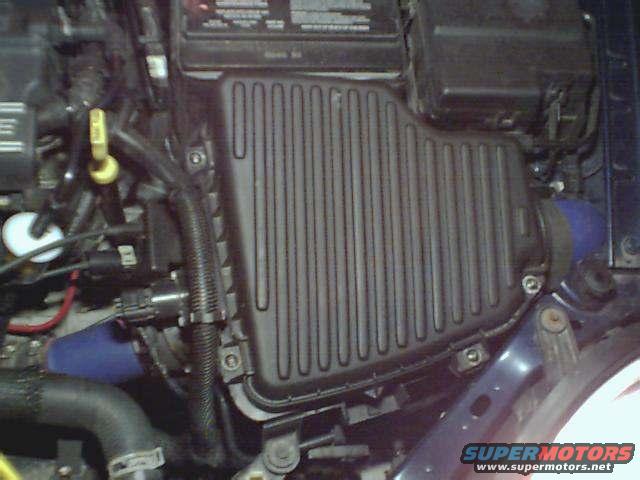 Engine bay showing black ribbed air filter housing and blue hose