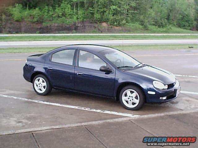 Dark blue sedan parked on pavement, trees in background
