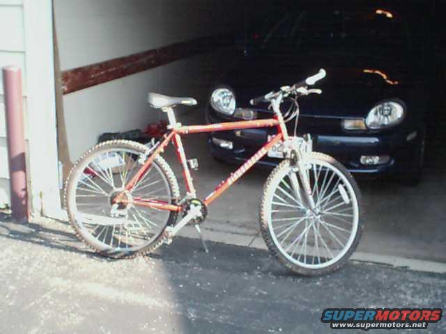 Front view of a dark 2000 Dodge Neon with a red bicycle in front