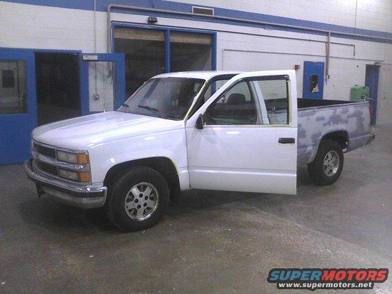 White pickup truck, driver's side front three-quarter view, primer on rear bed