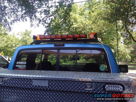 1992 Ford F-150 pickup truck rear view with diamond plate toolbox and amber light bar on roof