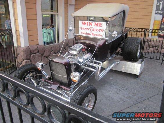 Hot rod with a large V8 engine and a sign that says 'WIN ME on PENNY SLOTS at Casino Royale'