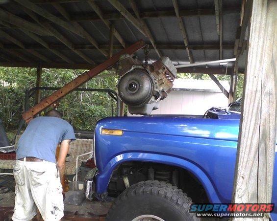 Blue 1985 Ford Bronco front fender and tire with engine hoist above