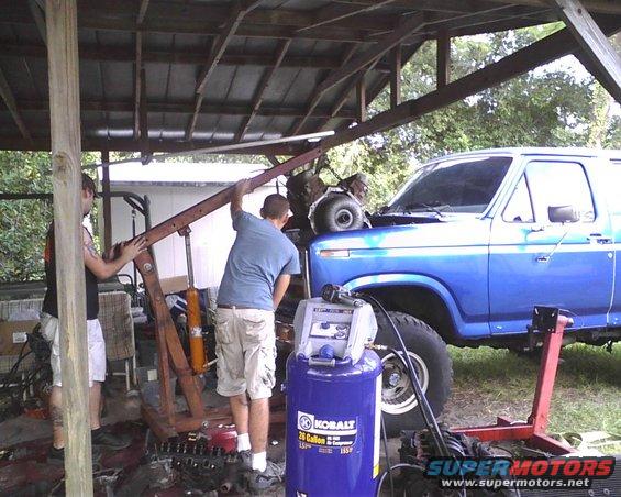 Blue Ford Bronco with hood open, engine hoist nearby. Kobalt air compressor visible