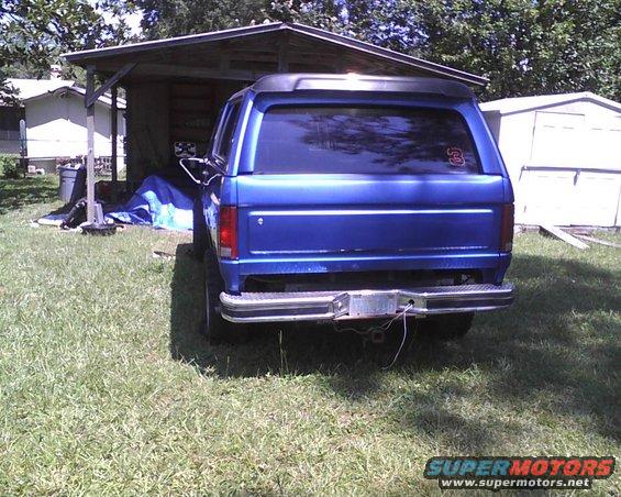 Blue SUV parked in front of a shed. Has a number 3 sticker on the rear window