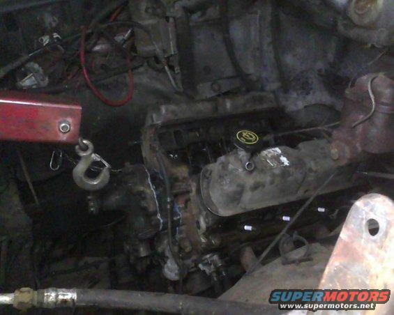 Engine bay with engine hoist hook attached to engine block. Supermotors.net logo visible