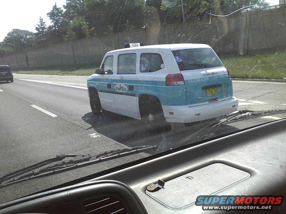 Rear view of a white and blue taxi van with a disabled symbol and 'FLASH CAB' text