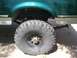 2004 Ford F-350 - Close-up of a truck's rear wheel and fender, showing off-road tires and green paint.
