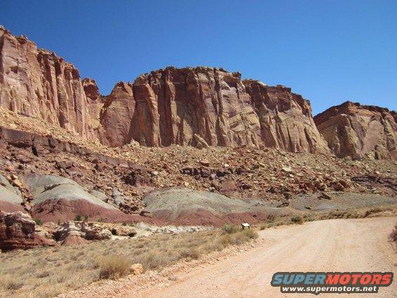 Desert landscape with red rock cliffs and a dirt road