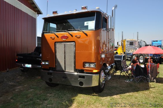 Front view of an orange semi-truck with a chrome bumper and grille. A sign with '42' is visible on the windshield