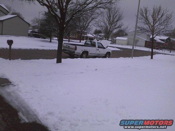 White pickup truck with hood open parked on a snow-covered street