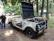 1962 International Scout 80 - A weathered International Scout sits in a wooded area with its hood open, revealing the engine.