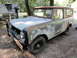 1962 International Scout 80 - This weathered SUV sits outdoors, showing significant rust and peeling paint, with a boat and trailer visible behind it.