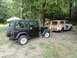 1962 International Scout 80 - A vintage 1962 International Scout 80, showing significant rust, is towed by a black Jeep Wrangler in a wooded area.