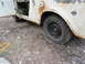 1962 International Scout 80 - This weathered off-road vehicle sits with its door ajar and a flat tire, showing signs of age and disuse.