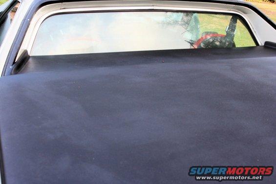 Black vinyl bedcover on a 1976 Ford Ranchero, showing the rear window with reflections