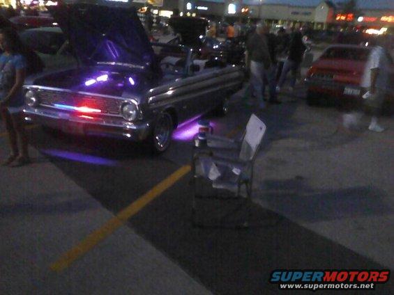 Classic car with hood open, purple and red underglow lights. Another car is visible to the right