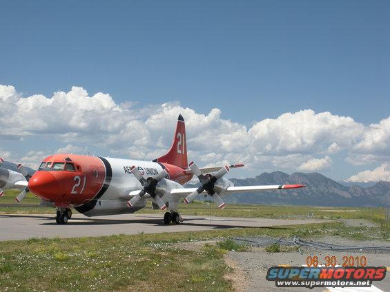 Four-engine turboprop aircraft with red nose and tail, marked '21'