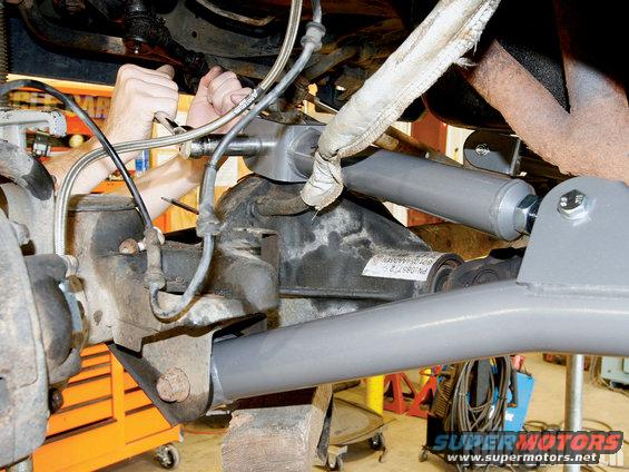 Close-up of vehicle's rear axle and suspension with gray painted components and a white label with text