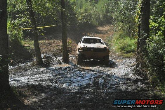 White SUV navigating a muddy off-road course
