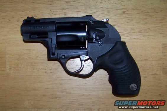 Black Taurus revolver with a ribbed grip, resting on a wooden surface