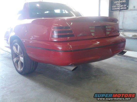 Red sedan with aftermarket taillights and spoiler, parked indoors
