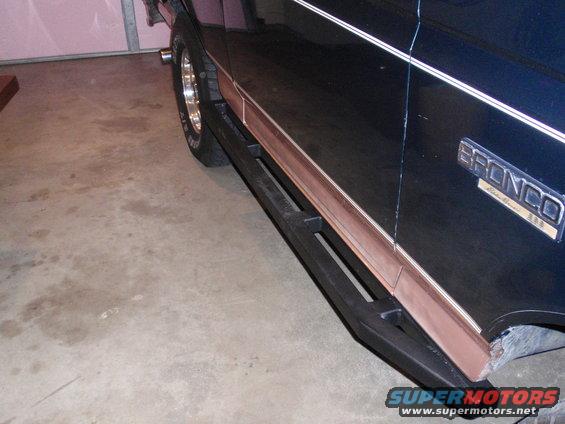 Dark blue 1995 Ford Bronco side view with aftermarket black step bars and copper trim