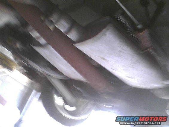 Vehicle underbody with exhaust pipe and suspension components visible, blurry