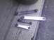 2003 Ford Crown Victoria - A set of four control arms, two aftermarket and two OEM, are displayed on a concrete surface.