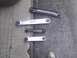 2003 Ford Crown Victoria - A collection of four vehicle control arms, two silver and two black, are displayed on a textured ground surface.