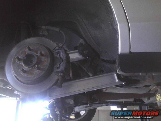 Underside view of a vehicle's rear brake rotor and caliper assembly