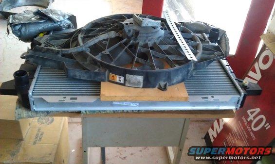 Radiator and fan assembly on a table, with boxes and a large TV box in the background