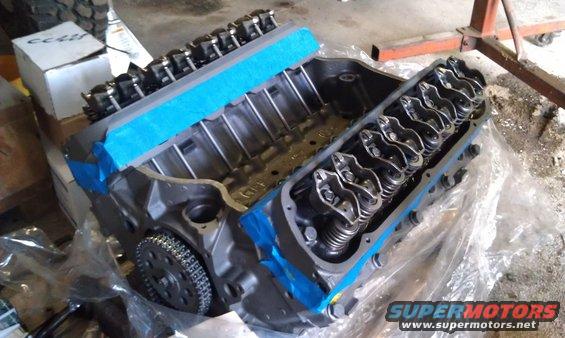 V8 engine block with valve train components and timing chain visible. Blue tape on the heads