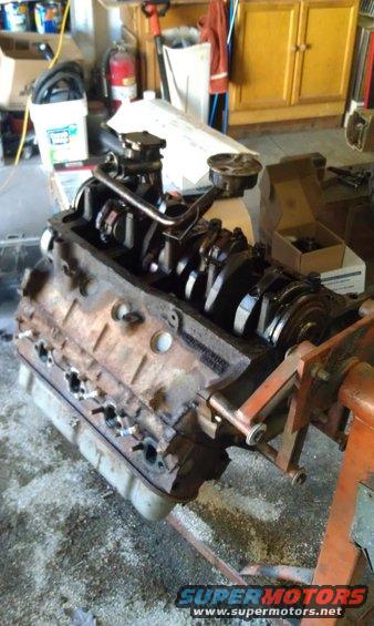 V8 engine block on an orange engine stand, showing crankshaft and pistons
