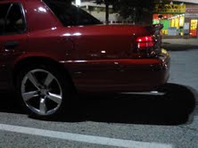 Red 1999 Ford Crown Victoria rear quarter panel with aftermarket wheels