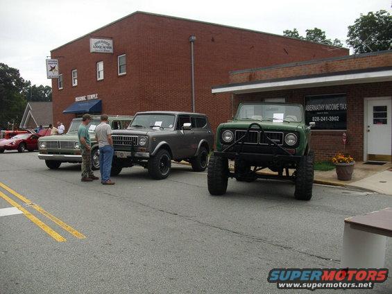 Green lifted SUV with large tires parked on street, front view