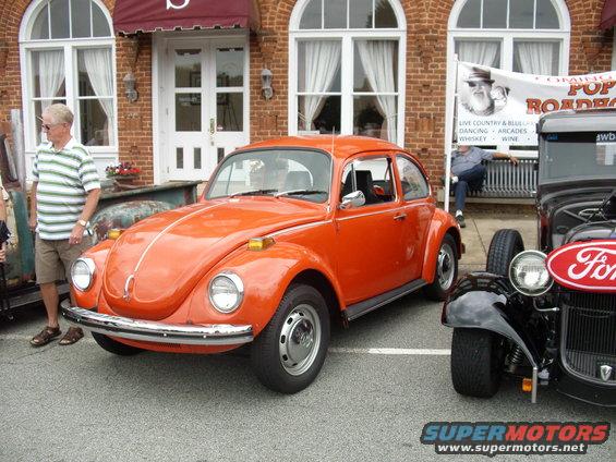Orange Volkswagen Beetle parked next to a Ford hot rod