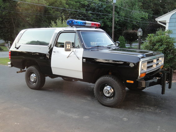 Black and white police SUV with light bar, 3/4 front view