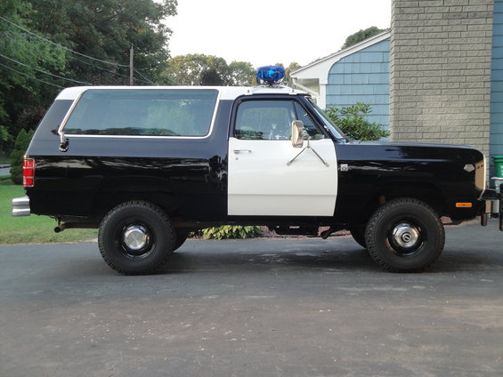 Black and white police SUV with a blue light bar on the roof, side view