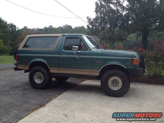 Green Ford Bronco with tan trim and aftermarket wheels parked on a driveway